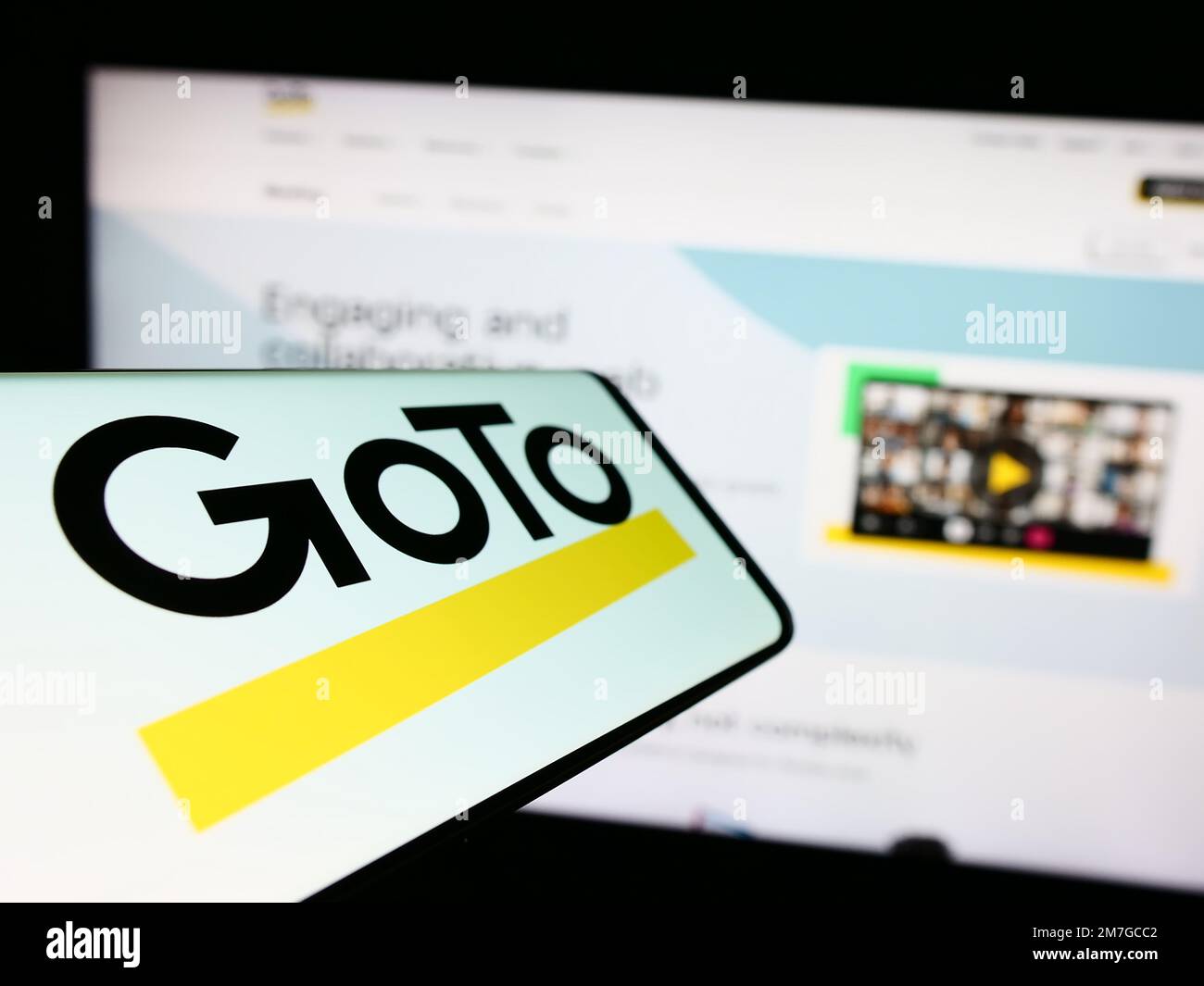 Smartphone with logo of American communications software company GoTo on screen in front of website. Focus on center--left of phone display. Stock Photo