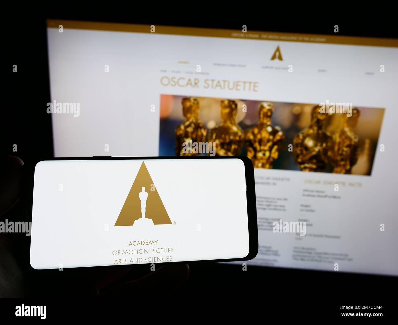 Person holding smartphone with logo of Academy of Motion Picture Arts and Sciences (AMPAS) on screen in front of website. Focus on phone display. Stock Photo