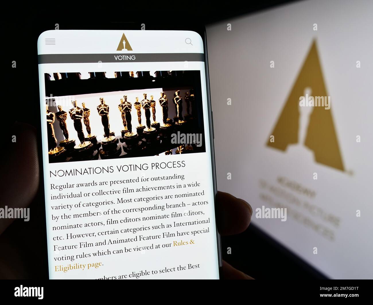 Person holding cellphone with webpage of Academy of Motion Picture Arts and Sciences (AMPAS) on screen with logo. Focus on center of phone display. Stock Photo