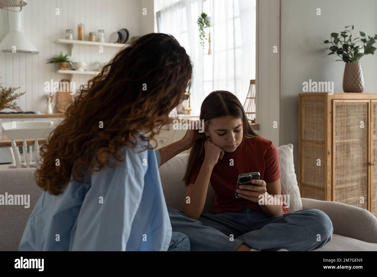 Uncommunicative teenager girl with phone in hands does not want to communicate with woman mother  Stock Photo