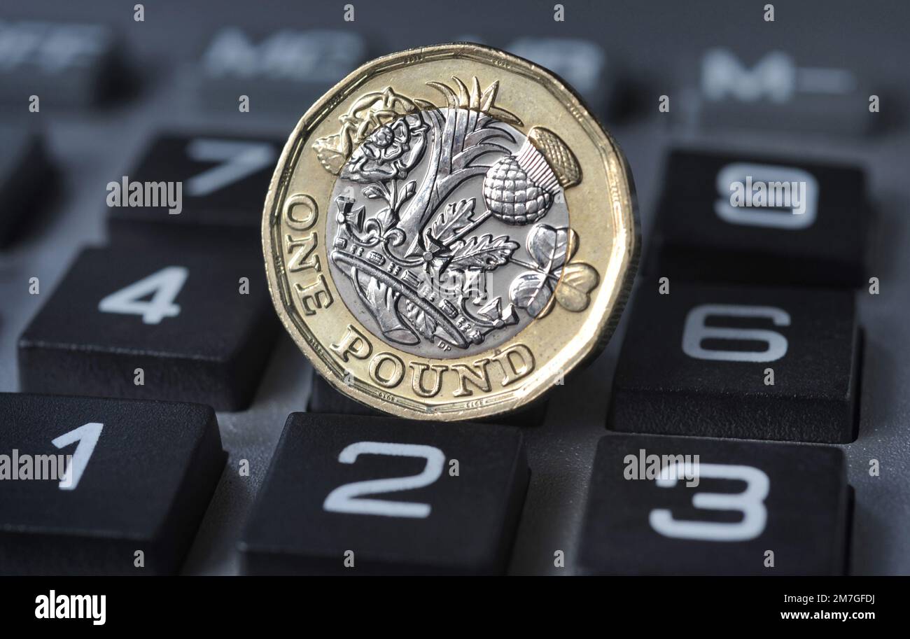 ONE POUND COIN ON CALCULATOR RE THE ECONOMY COST OF LIVING CRISIS FOOD COSTS MORTGAGES ETC UK Stock Photo