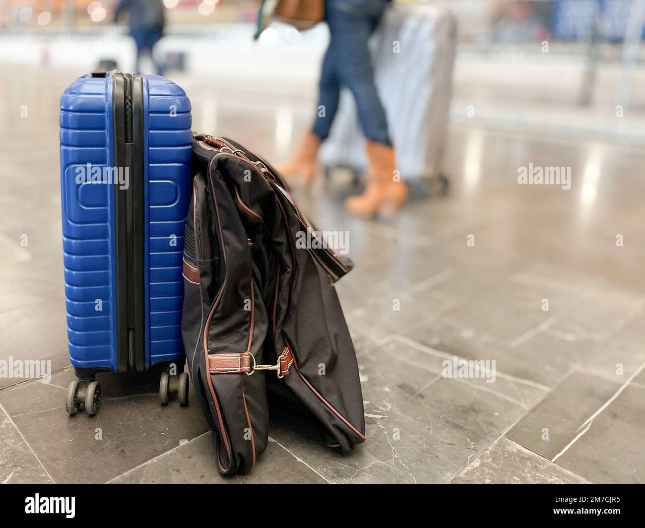 Blue suitcase and garment rack on the platform floor of a modern long