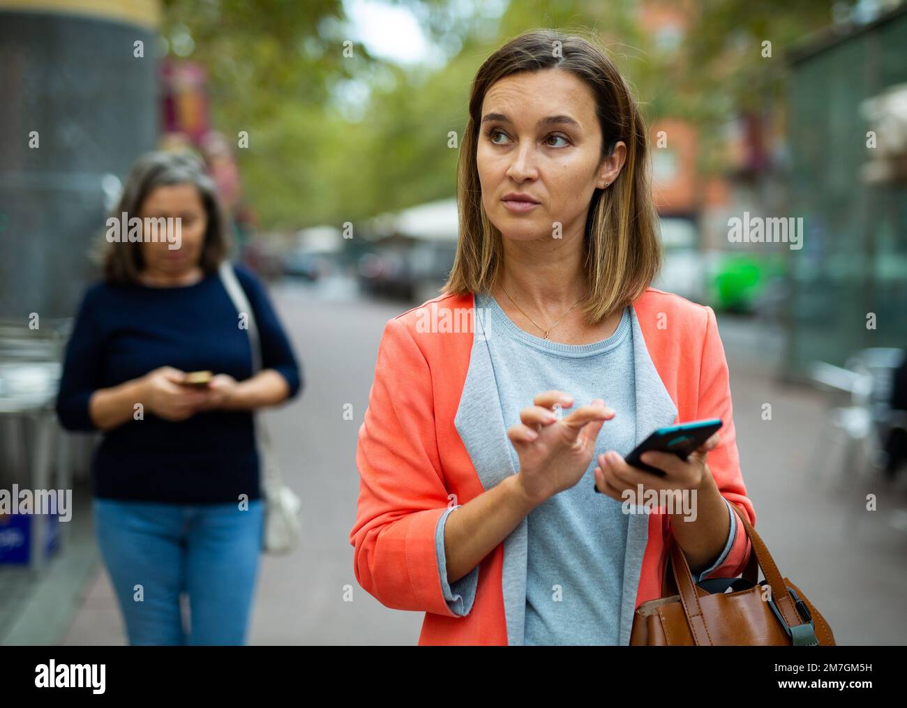 Focused young business woman using smartphone while walking outoors Stock Photo