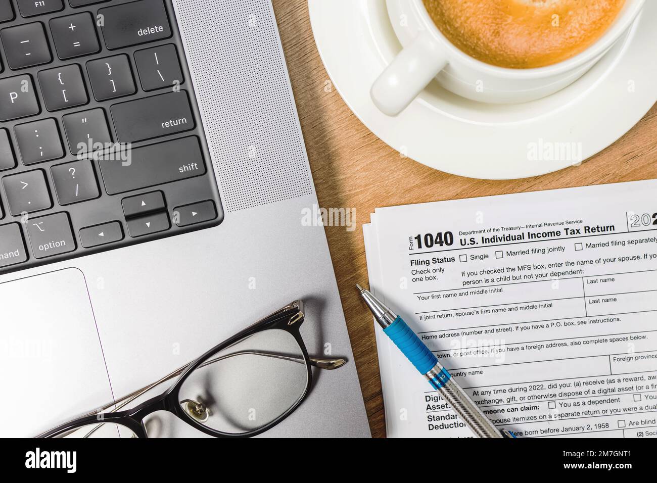 Laptop, coffee, pen and US individual tax form on the desk. Tax season