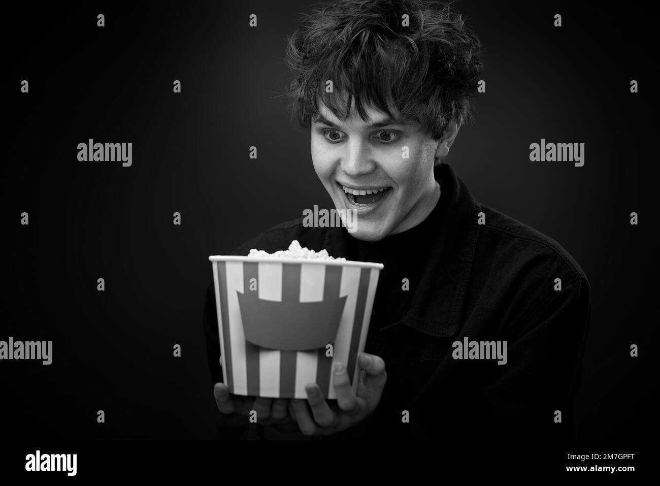 portrait of crazy young man holding bucket of popcorn Stock Photo