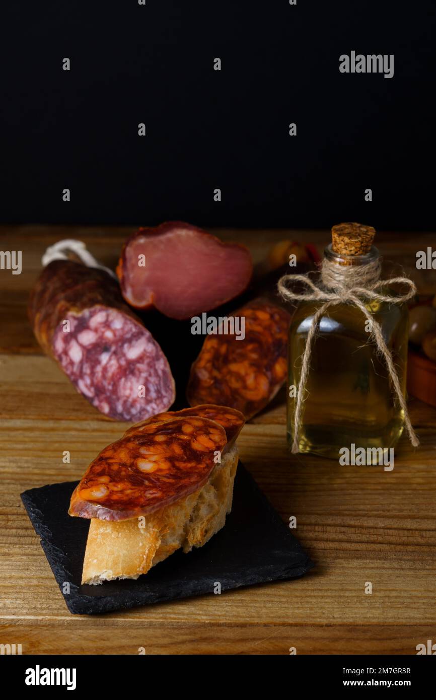 Tapa of iberian chorizo on rustic bread with olive oil on a black slate ...