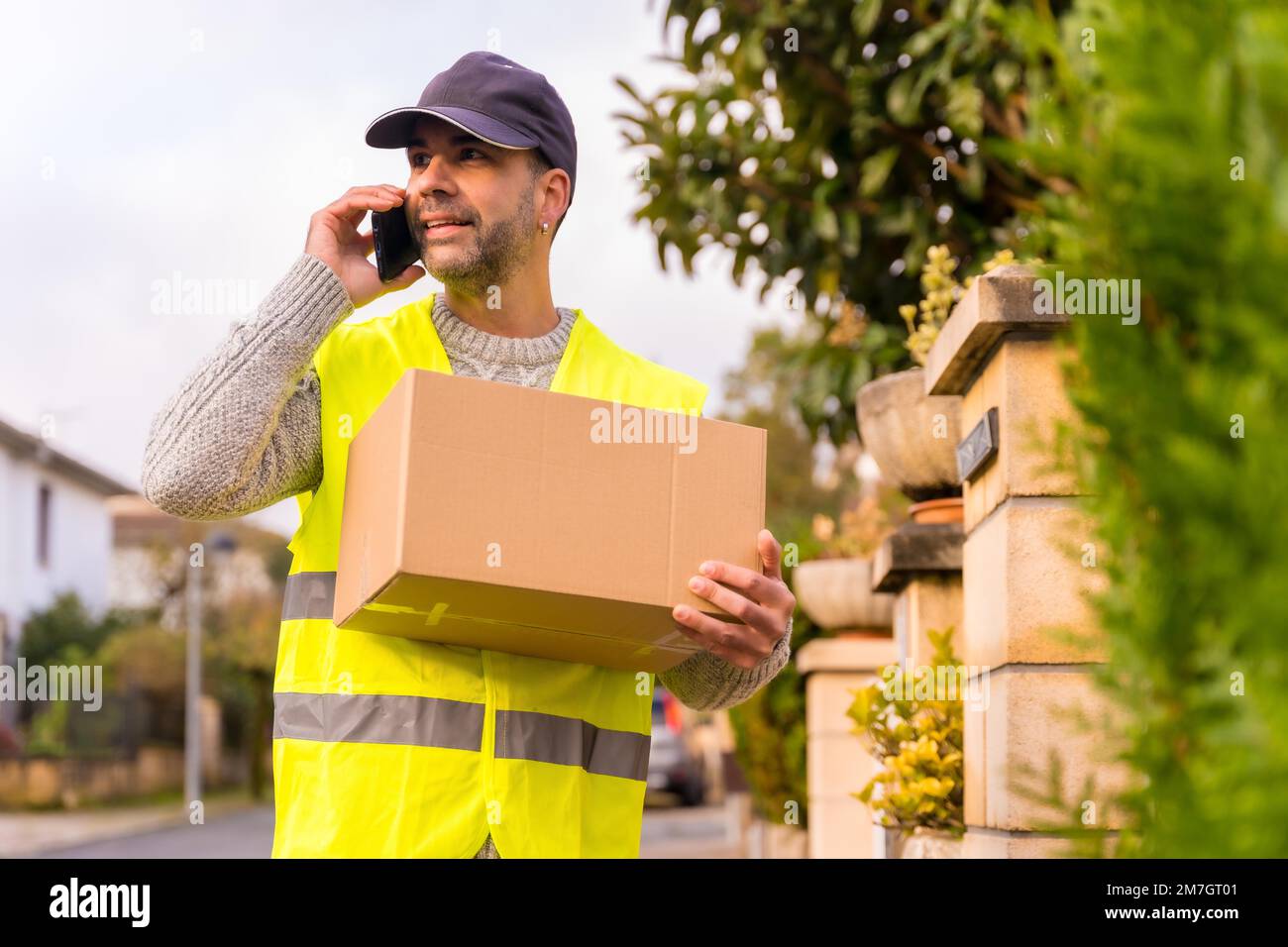 Package delivery carrier with a box from an online store, calling the