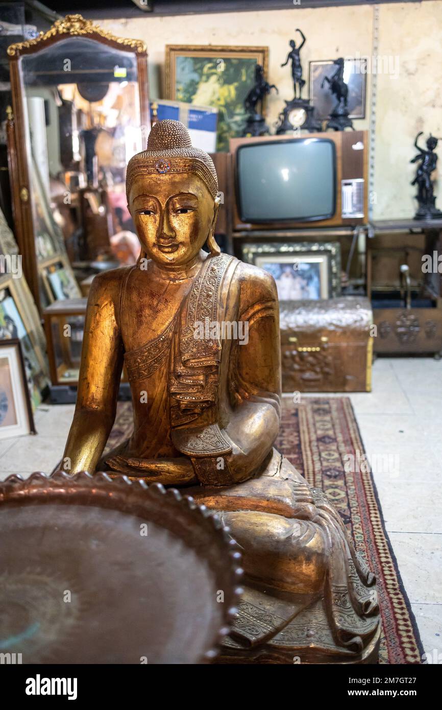 Copper figure of Buddha against the background of an old antique TV in