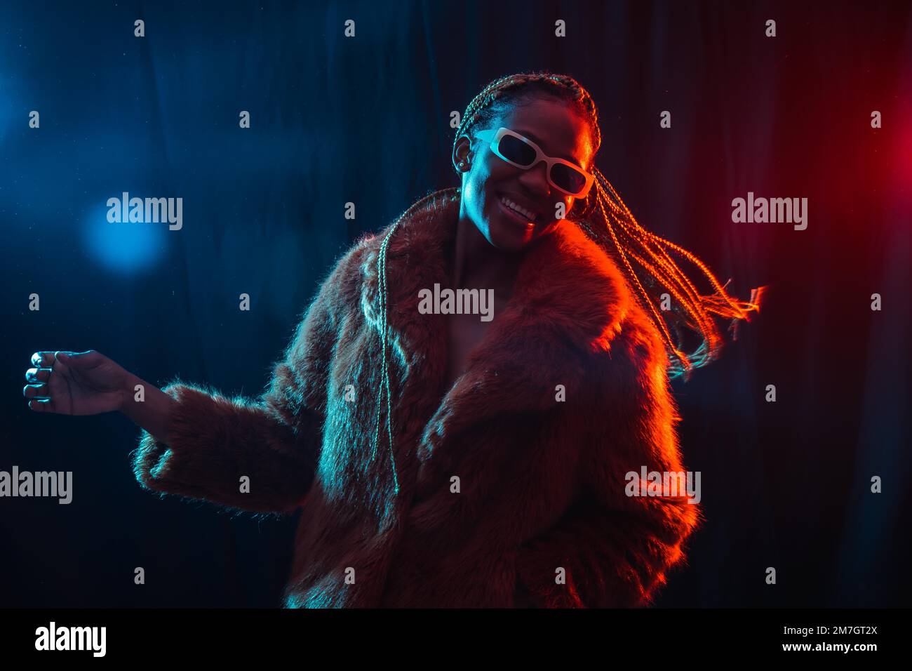 Black ethnic woman with braids with blue and red led lights, model having fun and dancing Stock Photo