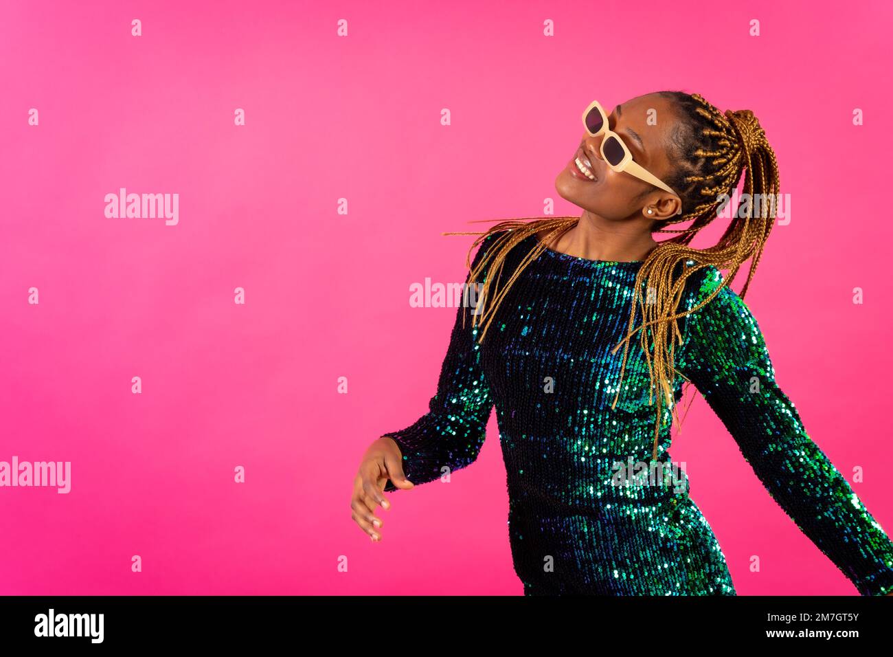 African young woman with party braids on a pink background, studio portrait having fun Stock Photo