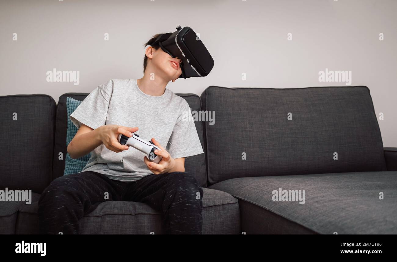 Boy having fun playing simulation games, using virtual reality headset and controller. Children and modern technology concept. Stock Photo