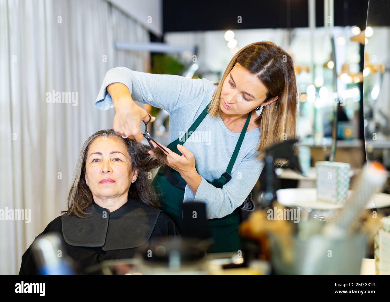 Woman hair stylist making haircut to elderly female client Stock Photo -  Alamy