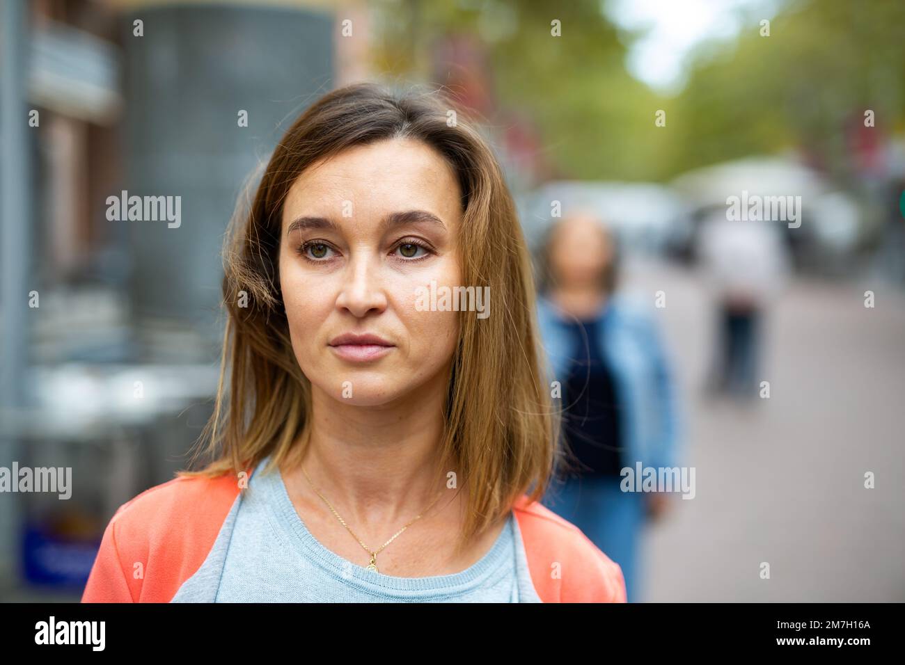 Portrait of brown-haired woman walking along city street Stock Photo