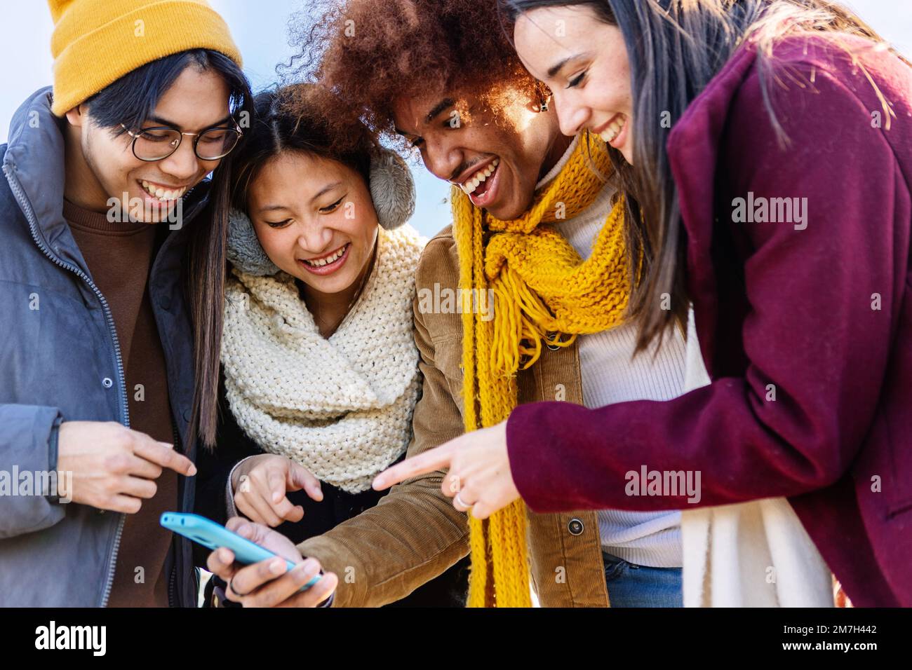Multiracial friends laughing together watching social media content on phone Stock Photo