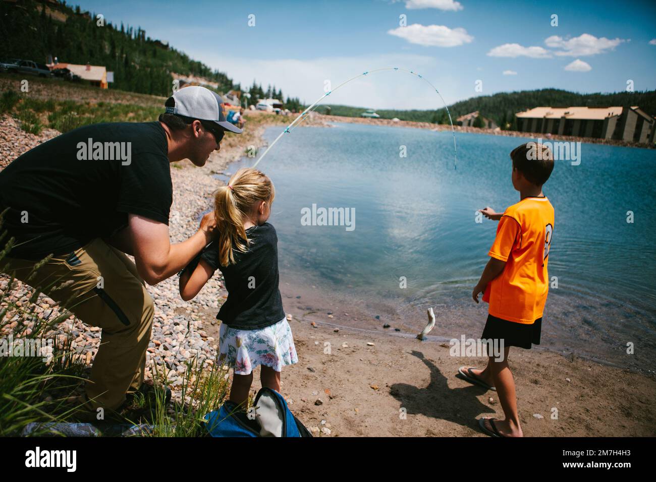Family catches a fish from a mountain lake on adventure vacation Stock Photo