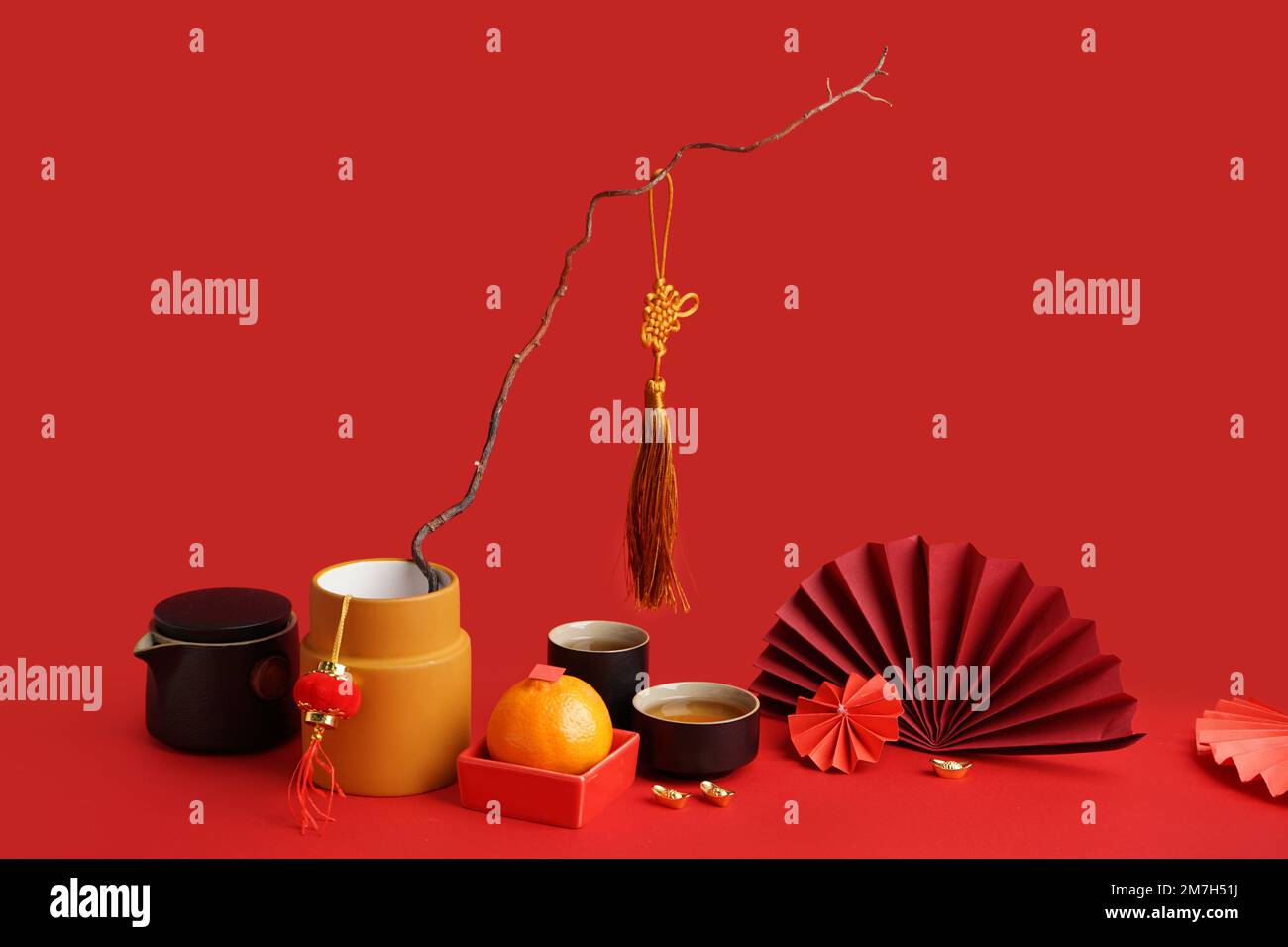 Teapot, cups of tea, mandarin, tree branch and Chinese symbols on red