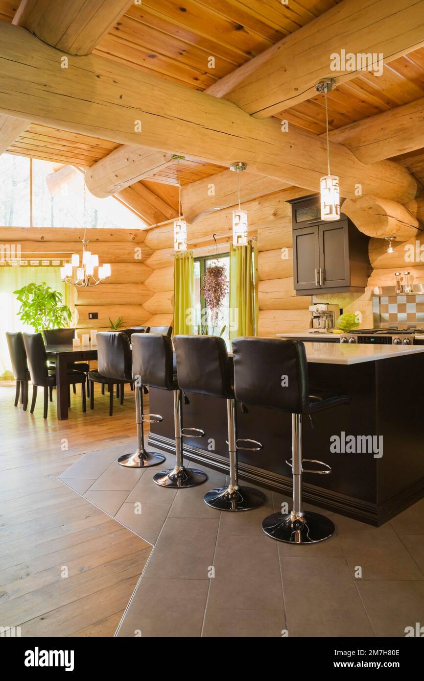 Island with white quartz countertop and black leather barstools in