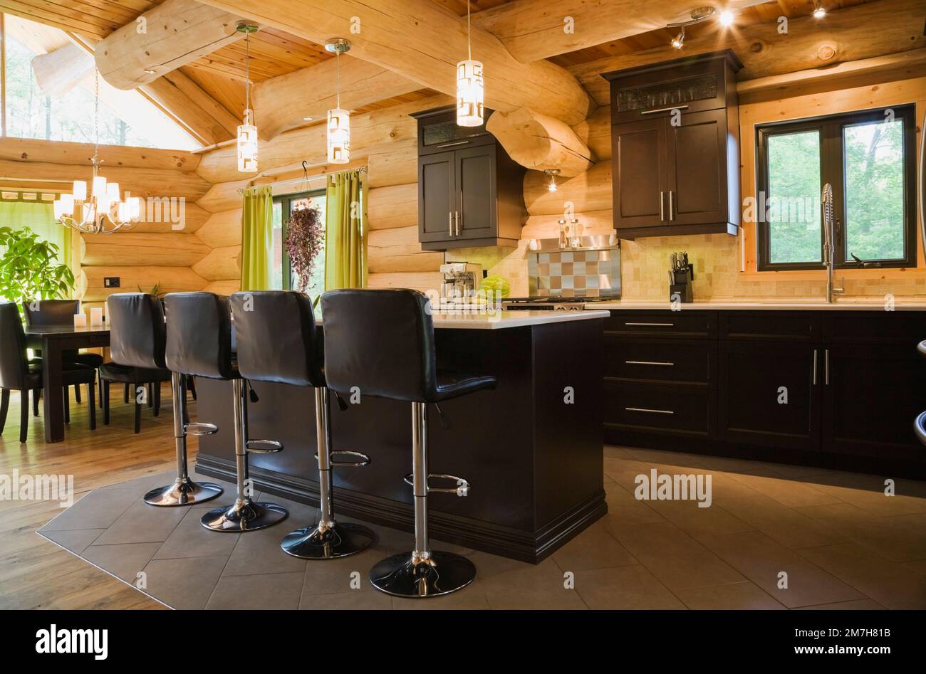 Island with white quartz countertop and black leather barstools in ...
