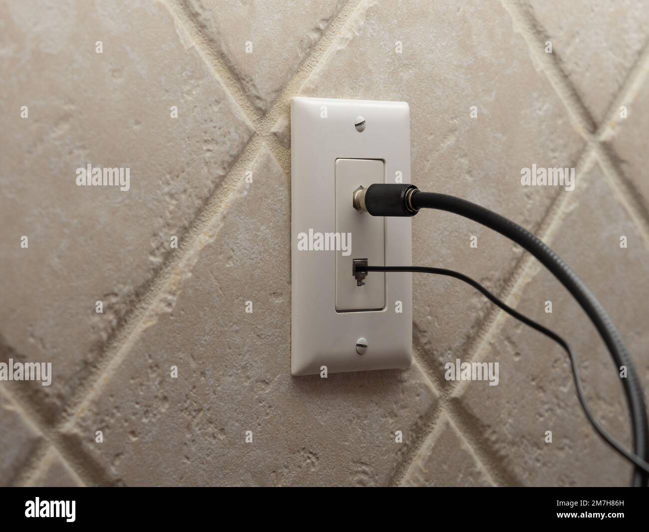 Coax cable cord and landline phone cord connected to wall outlet