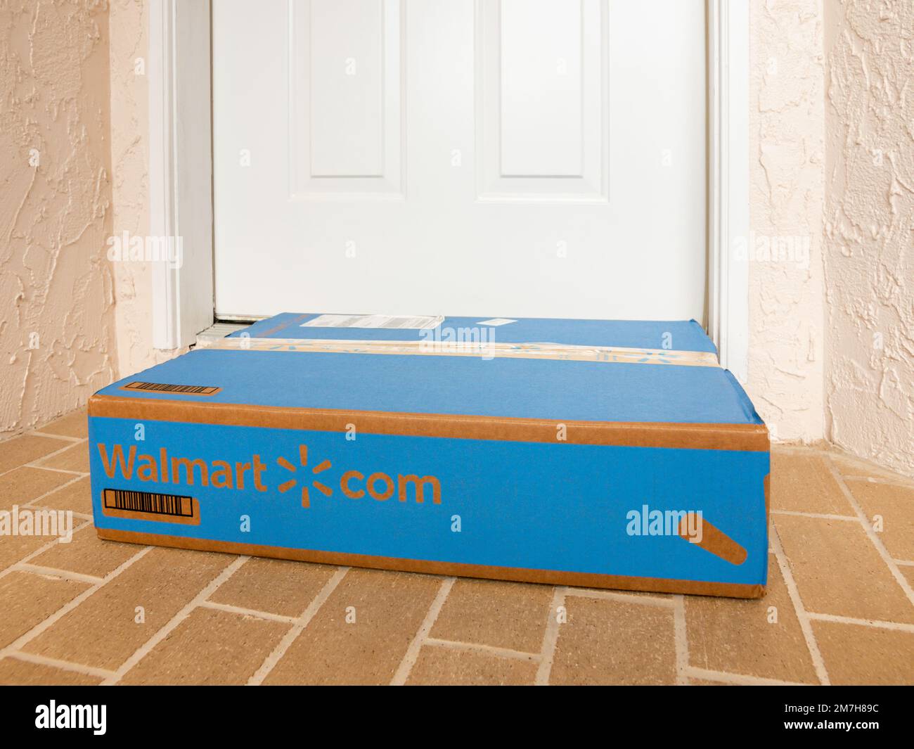 Walmart box delivered to residential doorstep. Walmart+ offers free package home delivery to it's members. Stock Photo