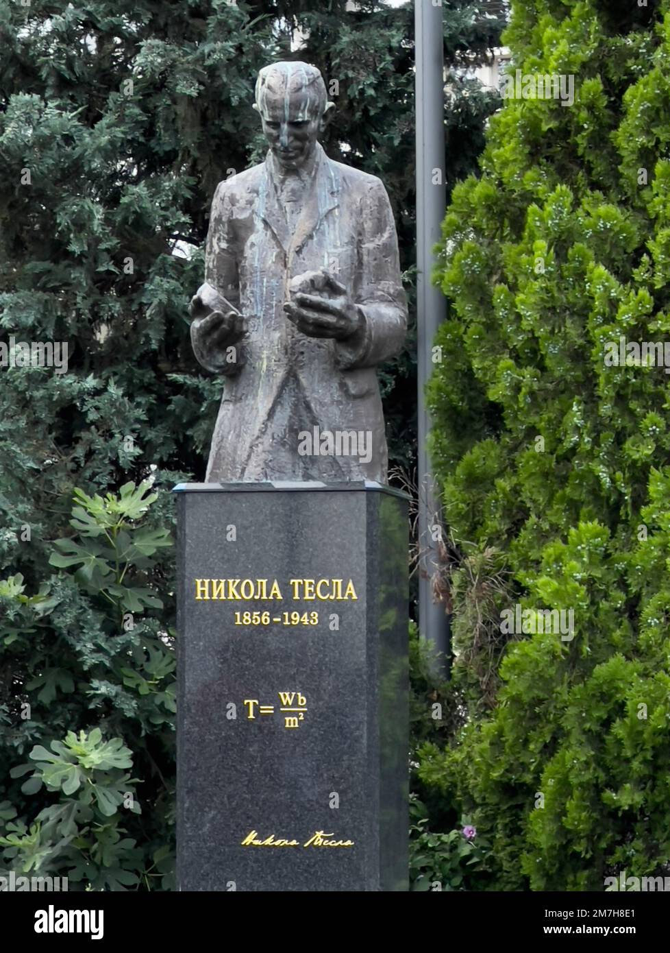 Defaced granite stone statue of Tesla in outdoor park in Belgrade, Serbia. Nicola Tesla, engineer and inventor, lived from 1856 - January 7, 1943. Stock Photo
