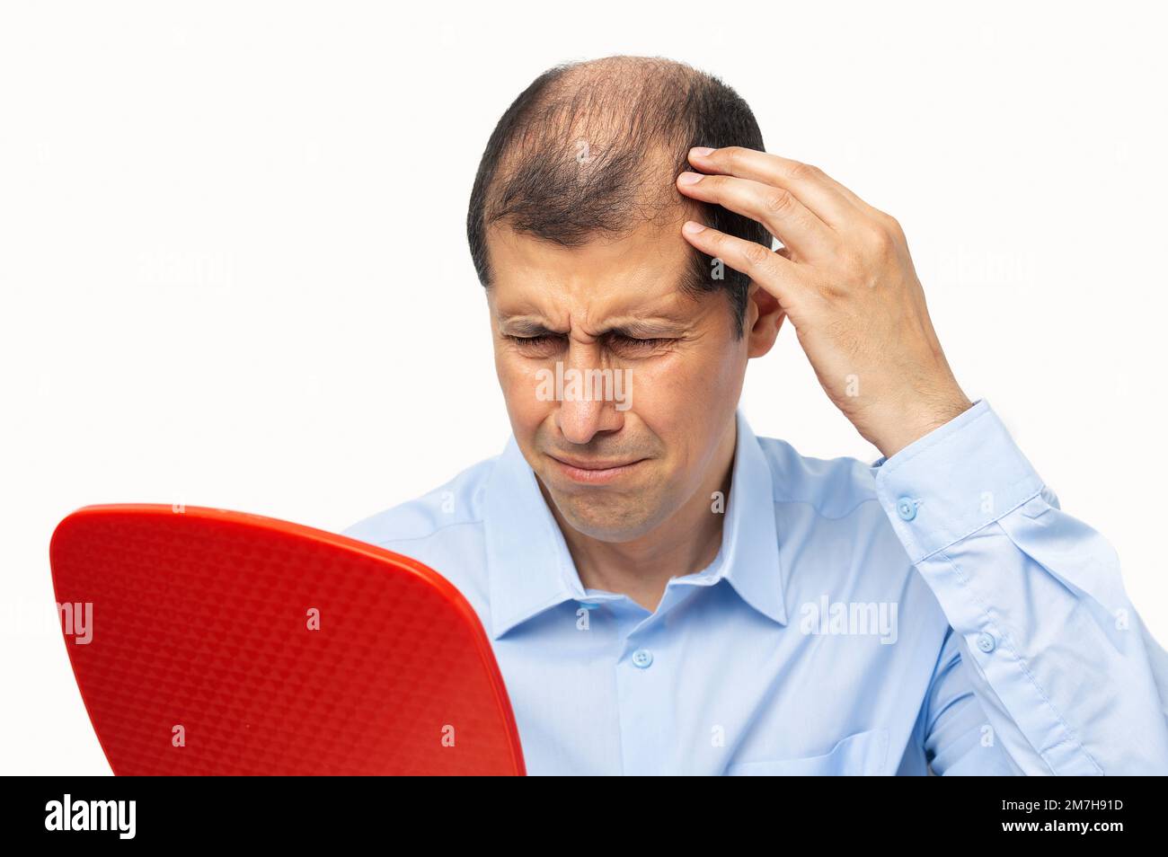 Upset middle aged man with alopecia looking at mirror, hair loss concept Stock Photo