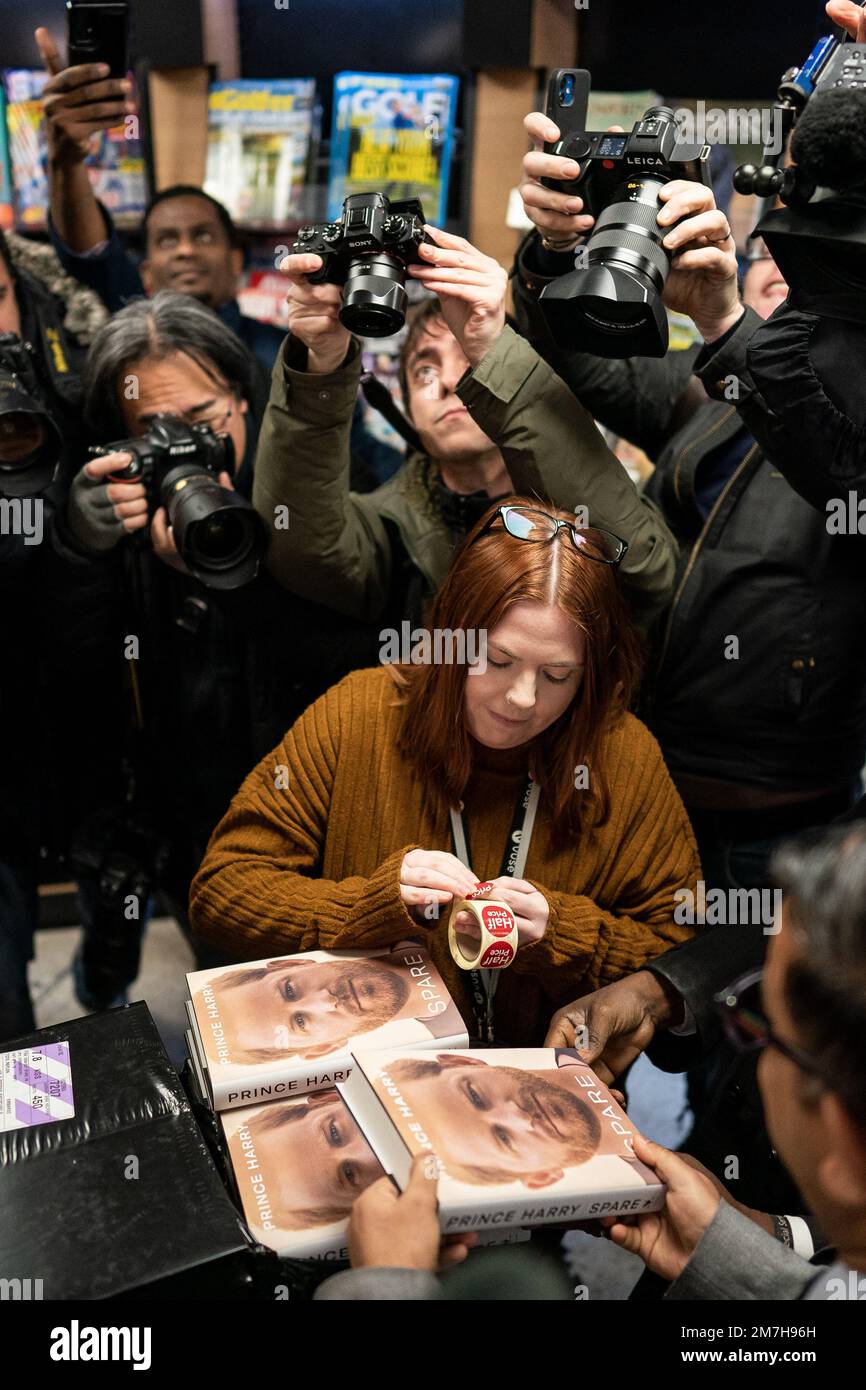 Members of the media take photos of a member of staff arranging the display of the newly released autobiography from the Duke of Sussex at WHSmith's in Victoria Station, London, where the book became available to purchase at midnight. Picture date: Tuesday January 10, 2023. Stock Photo