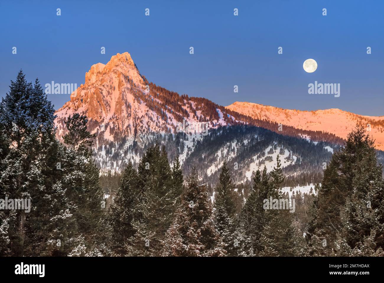 full moon setting over ross peak in the bridger mountains in winter