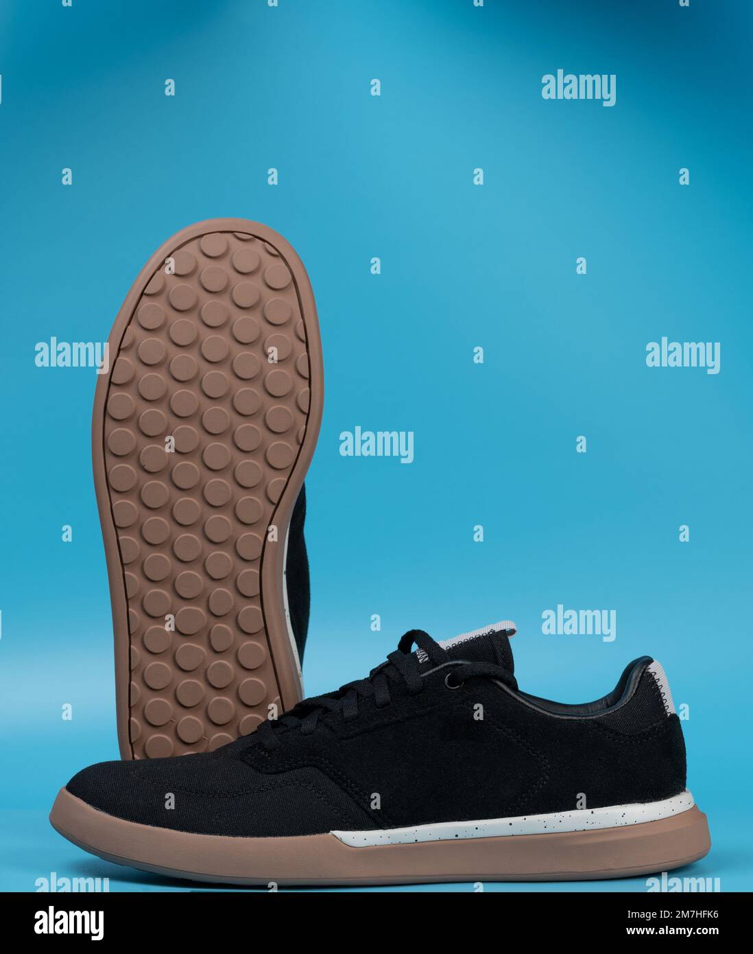 Modern trendy black pair sneakers shoes isolated on blue studio background Stock Photo