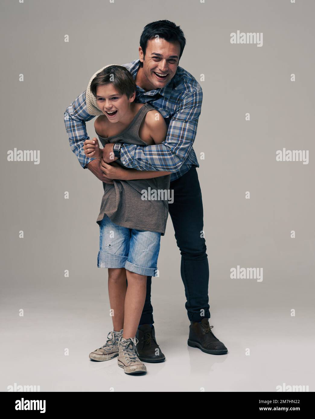 My dad is one of the dudes. Studio shot of a trendy father and son against a gray background. Stock Photo