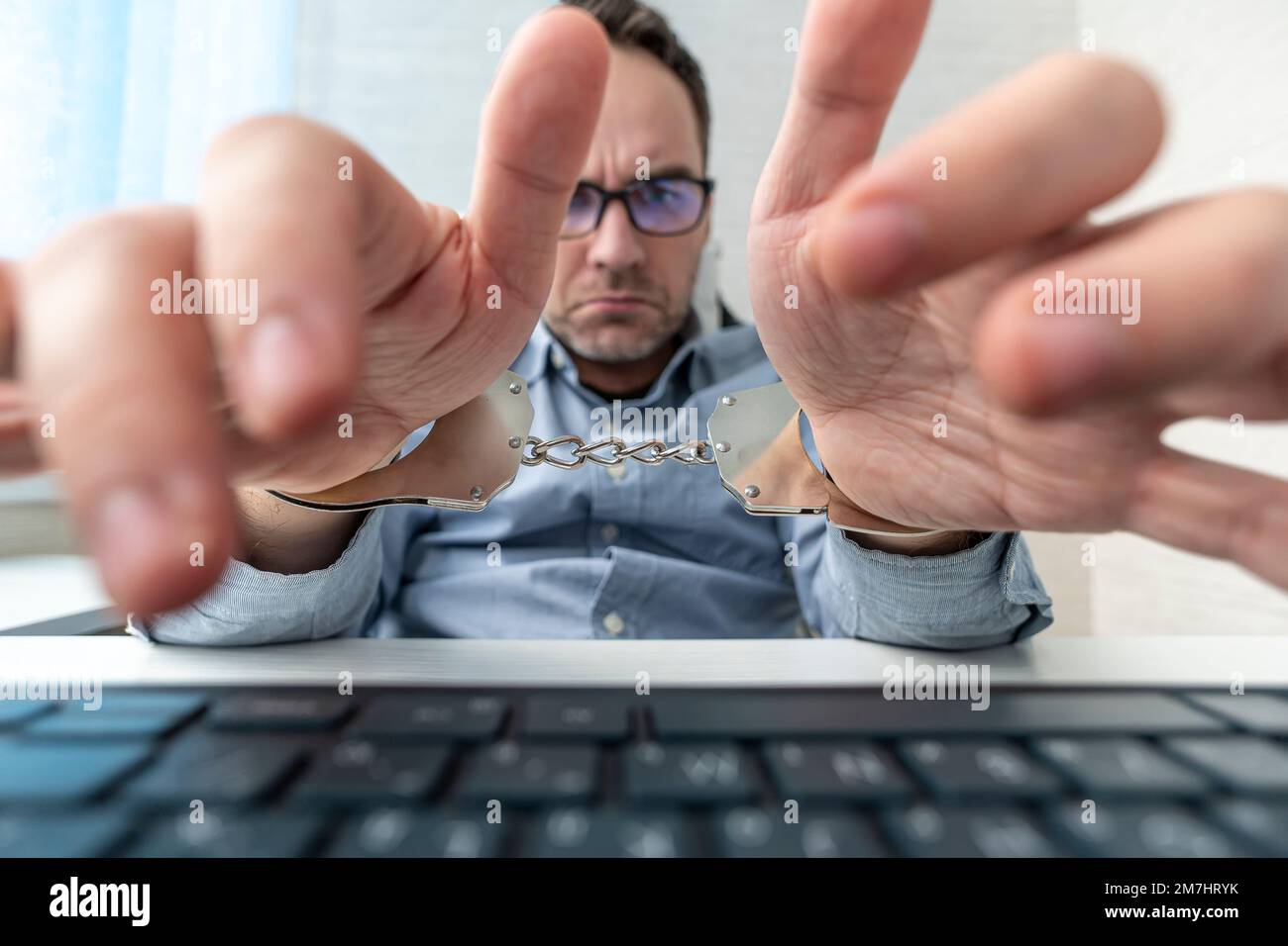 Man hands typing with handcuff locked on his wrist, conceptual workaholic. sad businessman in
