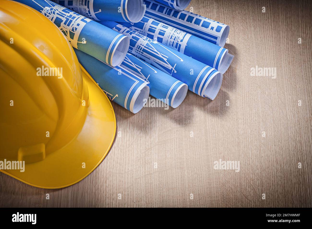 Blue rolled blueprints building helmet on wooden board construction ...