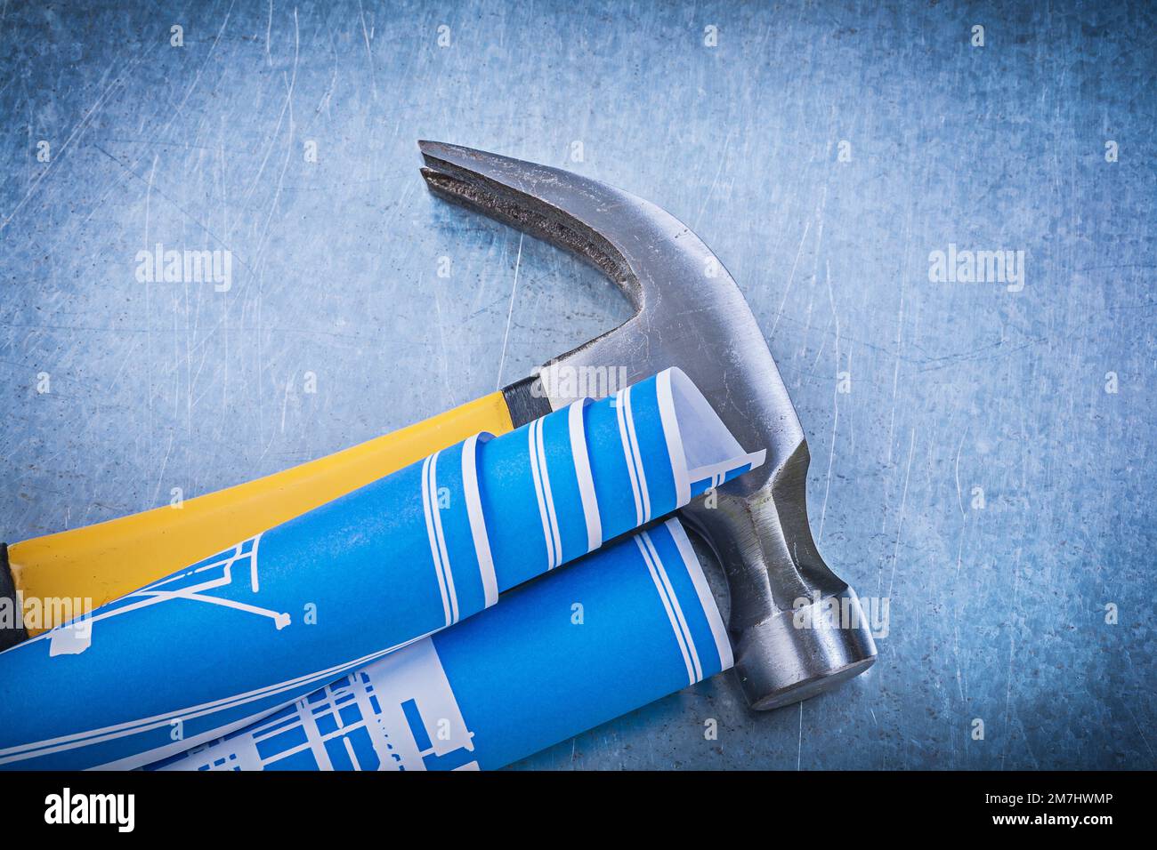 Blue rolled blueprints claw hammer on metallic background construction ...