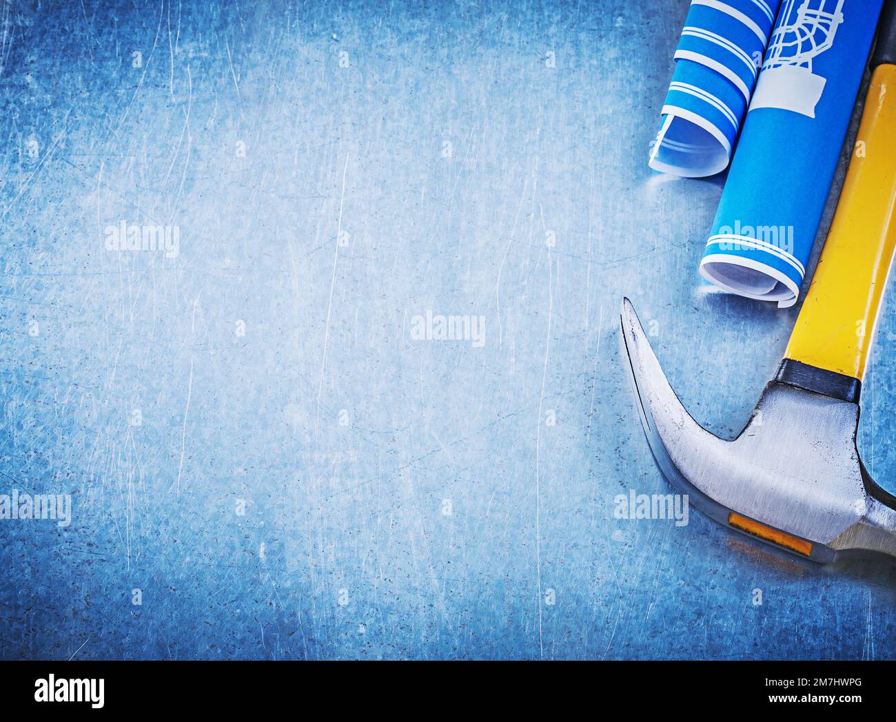 Blue rolled construction drawings claw hammer on metallic background ...