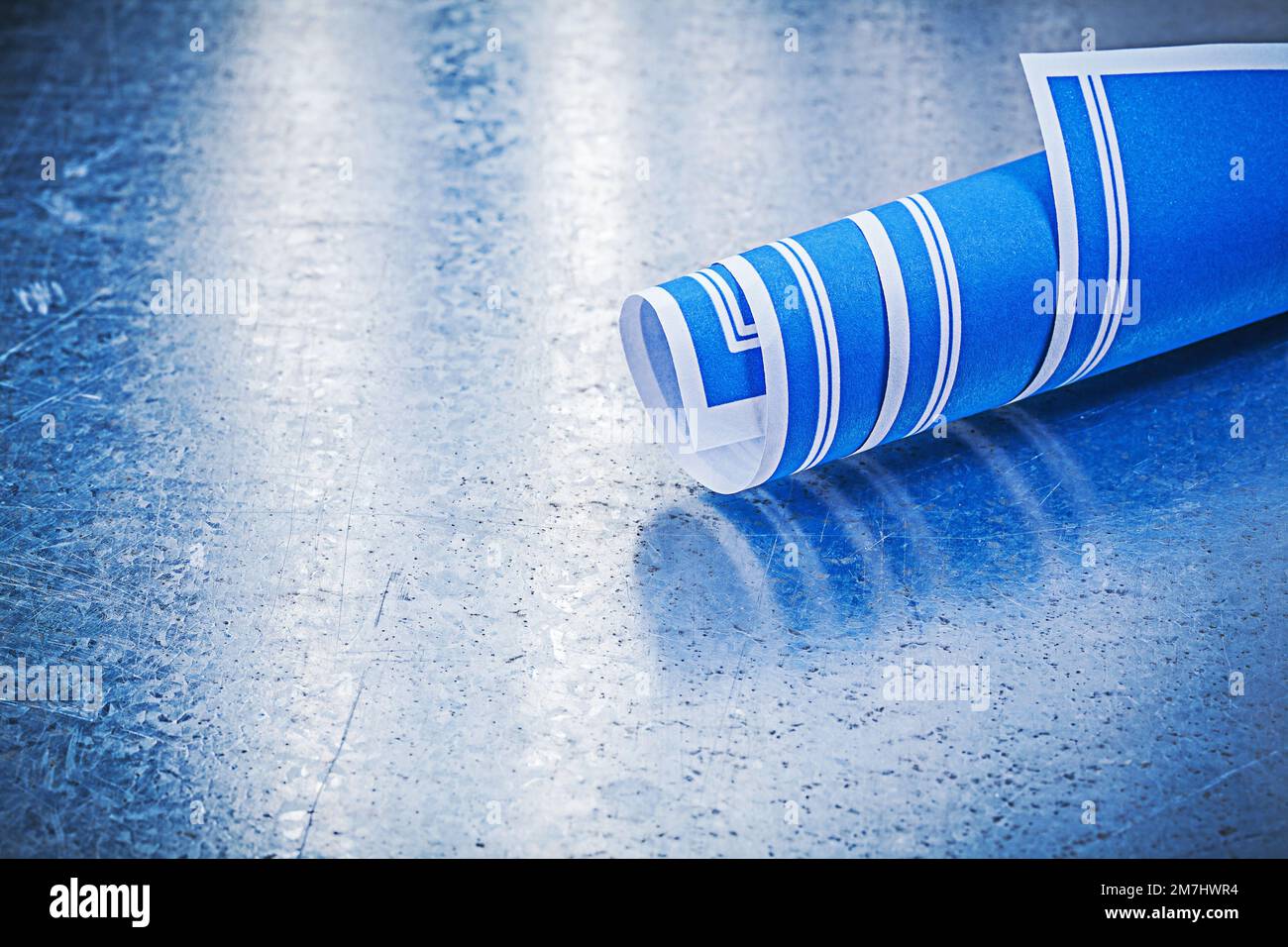 Blue rolled construction plans on metallic background Stock Photo - Alamy