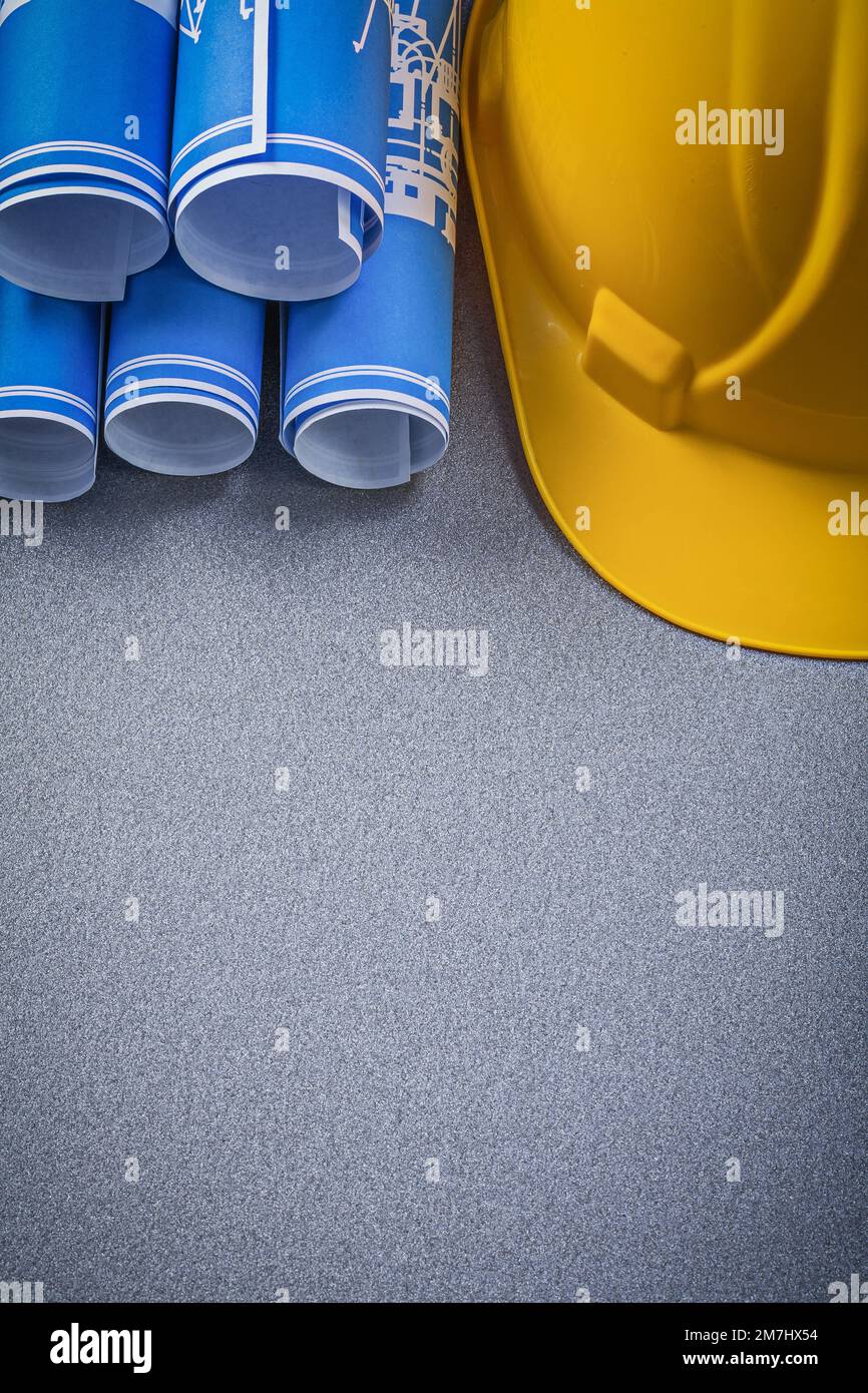 Building helmet blue rolled up construction drawings on grey background ...