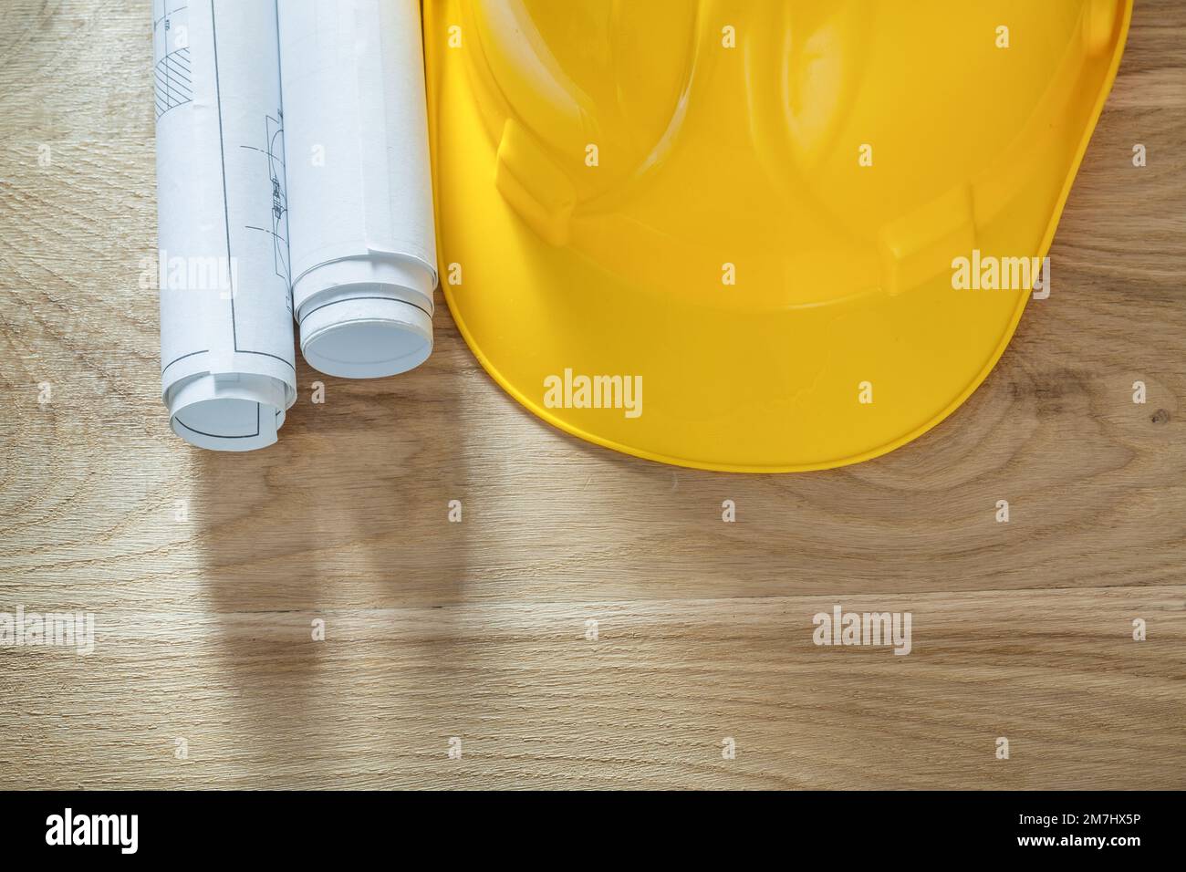 Building helmet rolled blueprints on wooden board Stock Photo - Alamy