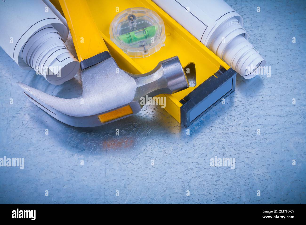 Close up image of rolled blueprints construction level claw hammer on ...