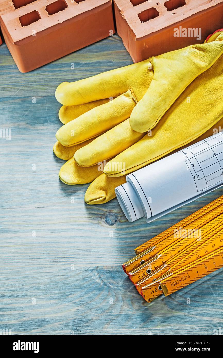 Composition of red bricks safety gloves blueprints wooden meter on wood ...
