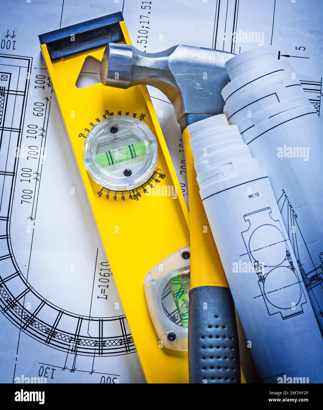 Construction level rolled up blueprints and claw hammer maintenance