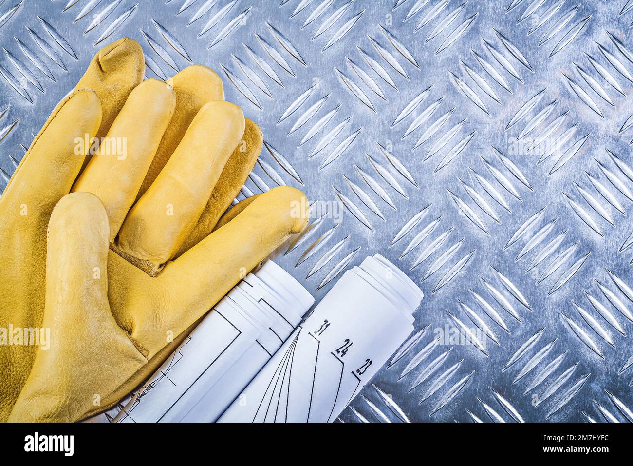 Engineering drawings leather safety gloves on fluted metal plate ...