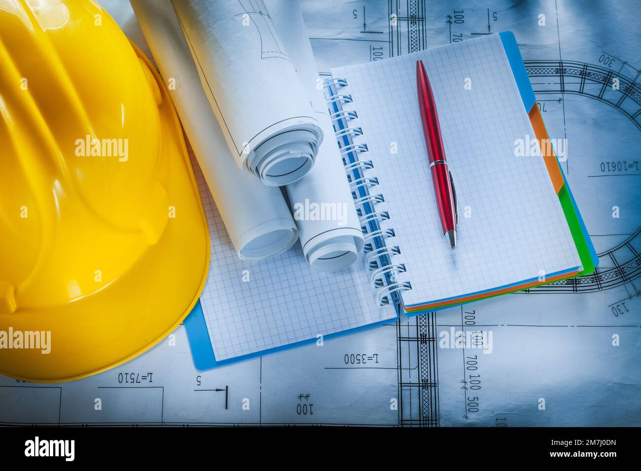 Protective hard hat checked notebook pen blueprints on construction plan. Stock Photo