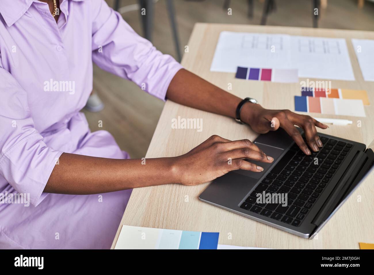 Side view closeup of black young woman using laptop while working on ...