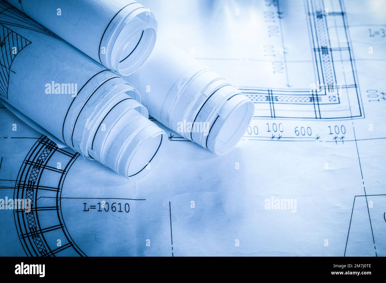 Rolled construction plans on blueprint. Stock Photo