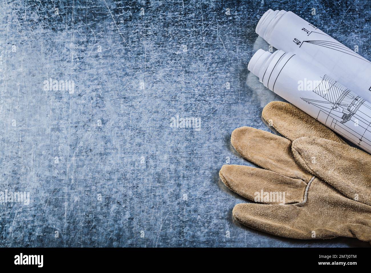 Rolled construction plans leather safety gloves on metallic background copy space. Stock Photo