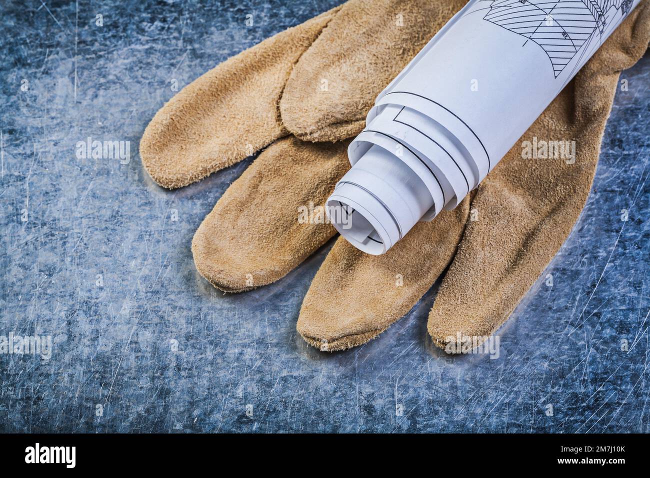 Rolled up engineering drawings leather protective gloves on metallic background construction concept. Stock Photo