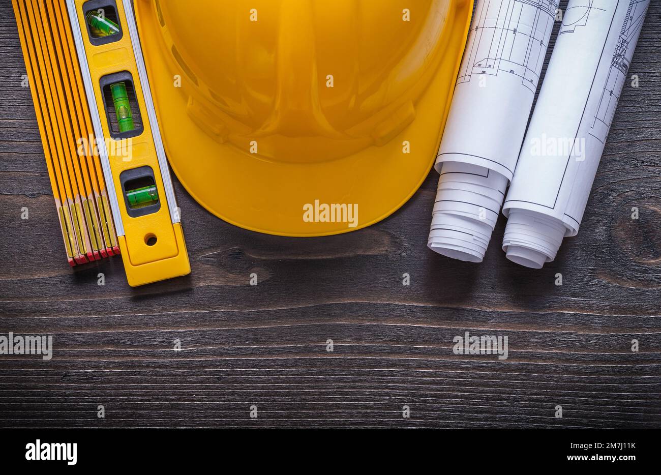 Rolls of blueprints construction level building helmet and wooden meter ...