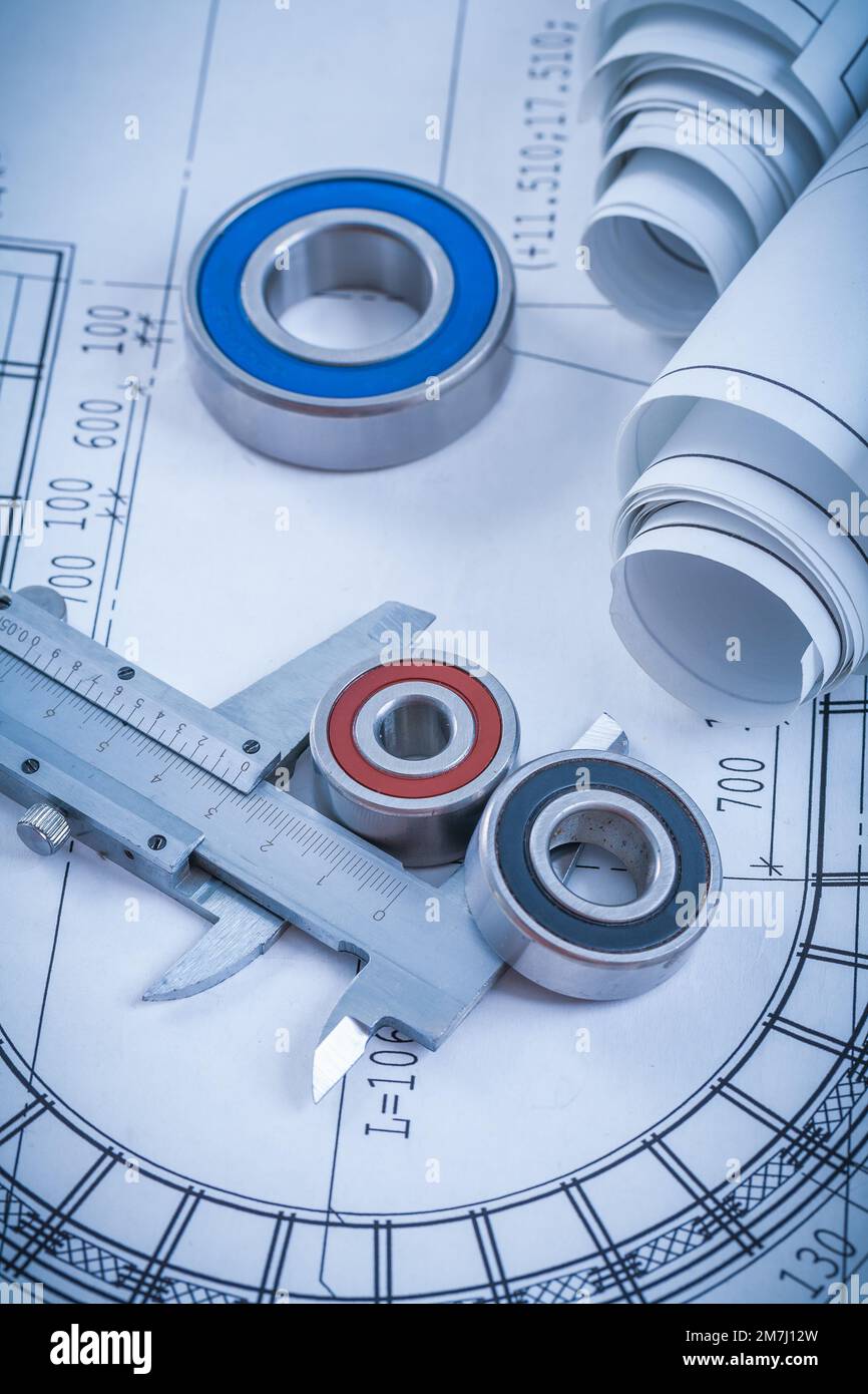 Rolls of construction drawings round rolling bearings and trammel caliper on blueprint industrial concept. Stock Photo