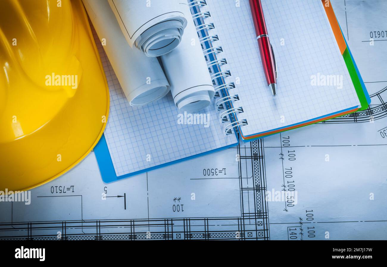 Safety hard hat checked notebook pen blueprints on construction plan. Stock Photo