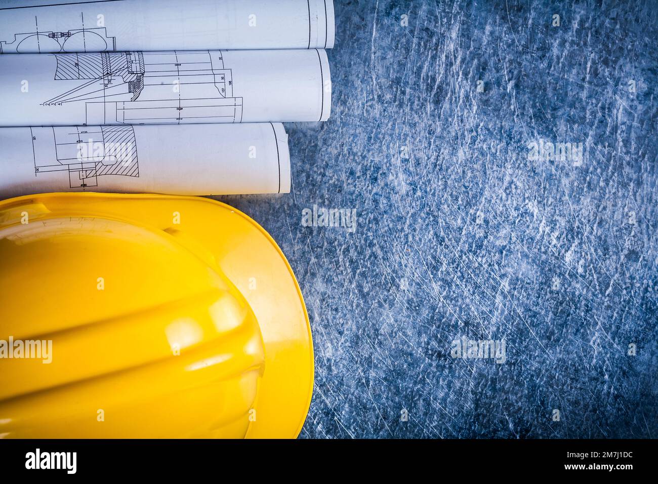 Set of white rolled up blueprints and construction helmet on metallic ...